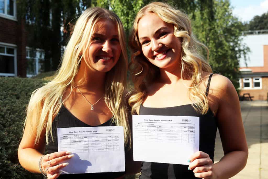 Two students celebrating results day at Priestley College with exam results in hand.